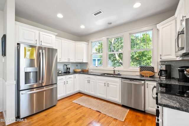 604 Currituck Way, Bald Head Island, NC 28461 - kitchen featuring appliances with stainless steel finishes, white cabinetry, decorative backsplash, light wood finished floors, and recessed lighting