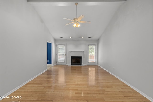 unfurnished living room with ceiling fan, light hardwood / wood-style flooring, high vaulted ceiling, and beam ceiling