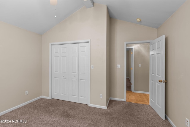 unfurnished bedroom with a closet, carpet flooring, ceiling fan, and vaulted ceiling with beams