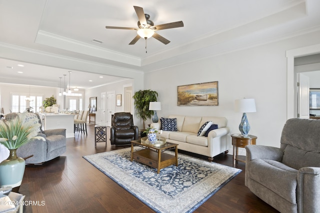 living area with crown molding, visible vents, a raised ceiling, and dark wood finished floors