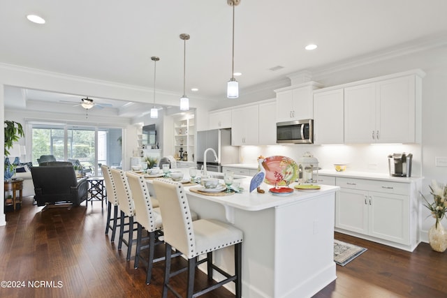 kitchen featuring a breakfast bar, dark wood finished floors, stainless steel microwave, ornamental molding, and fridge