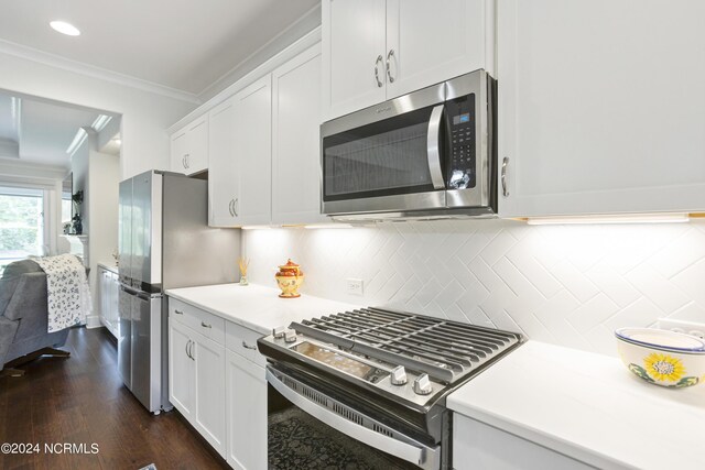 kitchen with dark hardwood / wood-style flooring, appliances with stainless steel finishes, tasteful backsplash, ornamental molding, and white cabinetry