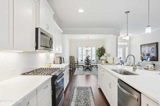 kitchen with appliances with stainless steel finishes, dark wood finished floors, a sink, and ornamental molding