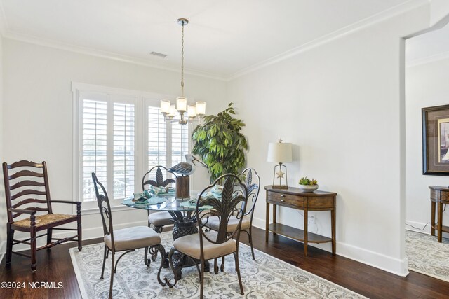 dining area with dark wood-type flooring, a chandelier, and crown molding