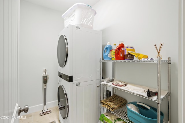 washroom with stacked washer and dryer, laundry area, and baseboards