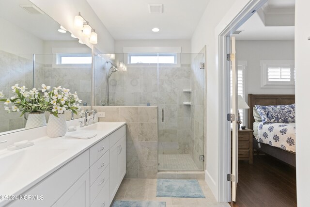 bathroom featuring wood-type flooring, double vanity, a healthy amount of sunlight, and a shower with door