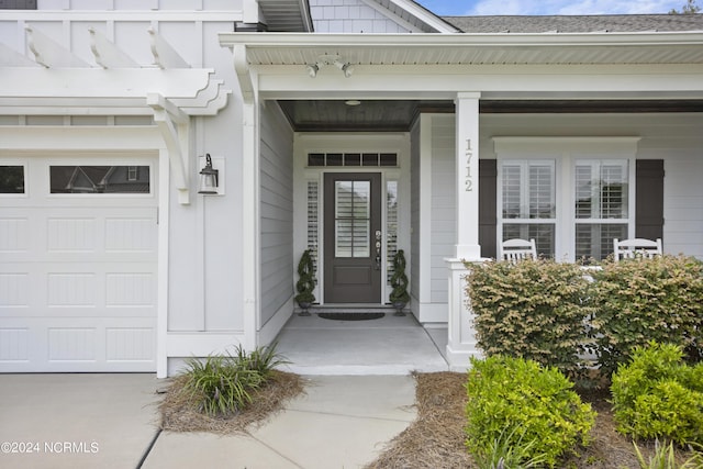 doorway to property with a garage and a porch