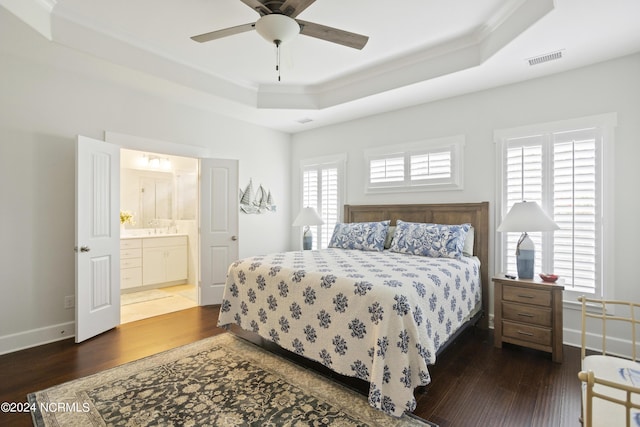 bedroom featuring a tray ceiling, wood finished floors, visible vents, and crown molding