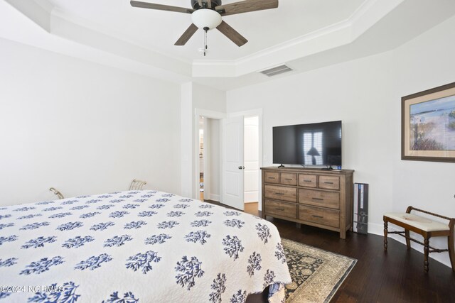 bedroom with ceiling fan, crown molding, a raised ceiling, and dark hardwood / wood-style floors