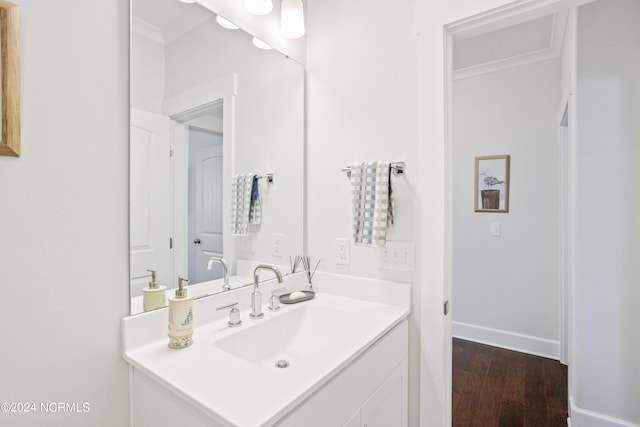 bathroom featuring baseboards, ornamental molding, wood finished floors, and vanity