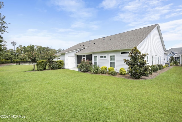 rear view of property featuring a yard and a shingled roof