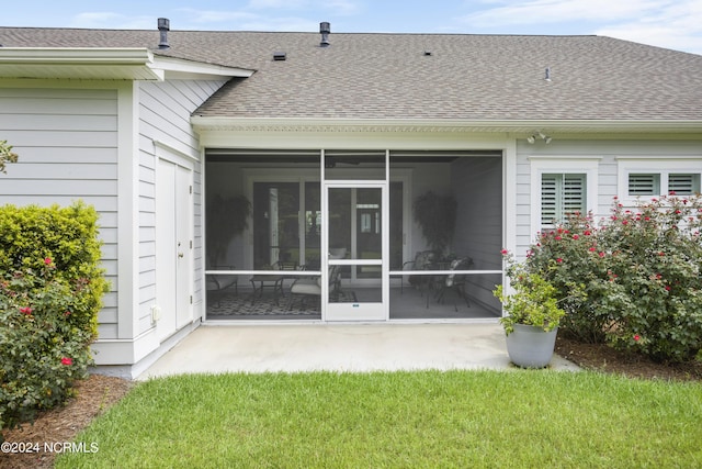 back of property with a shingled roof and a sunroom