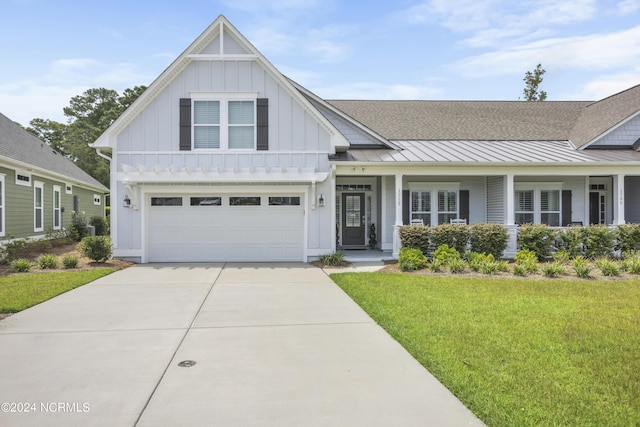 view of front of home with a garage, driveway, board and batten siding, a standing seam roof, and a front yard