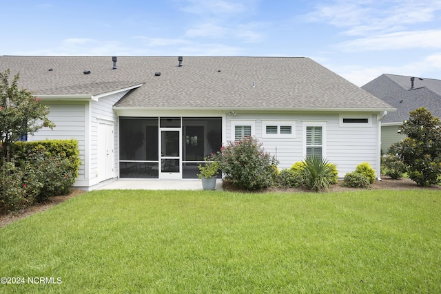 back of house with a shingled roof, a sunroom, and a lawn