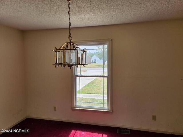 unfurnished dining area featuring a notable chandelier and a textured ceiling