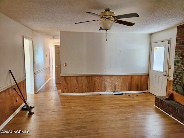 empty room featuring light hardwood / wood-style floors, a textured ceiling, and wood walls