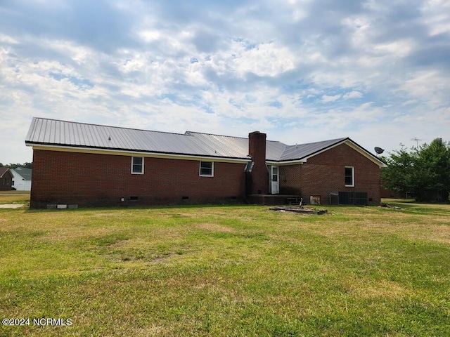 back of house with a lawn and central air condition unit