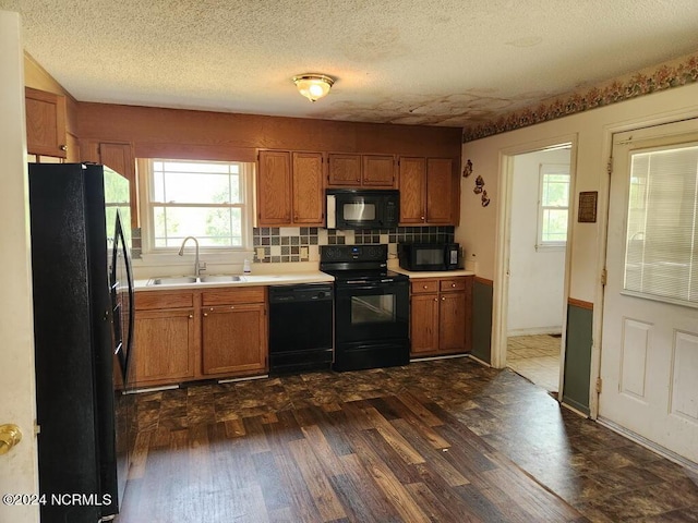 kitchen featuring sink, tasteful backsplash, a textured ceiling, dark hardwood / wood-style floors, and black appliances