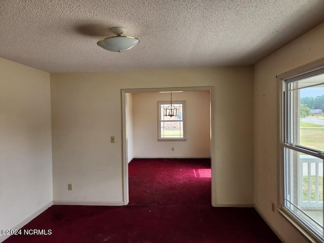 spare room featuring dark carpet and a textured ceiling