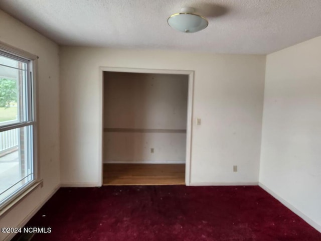 unfurnished room featuring dark colored carpet and a textured ceiling