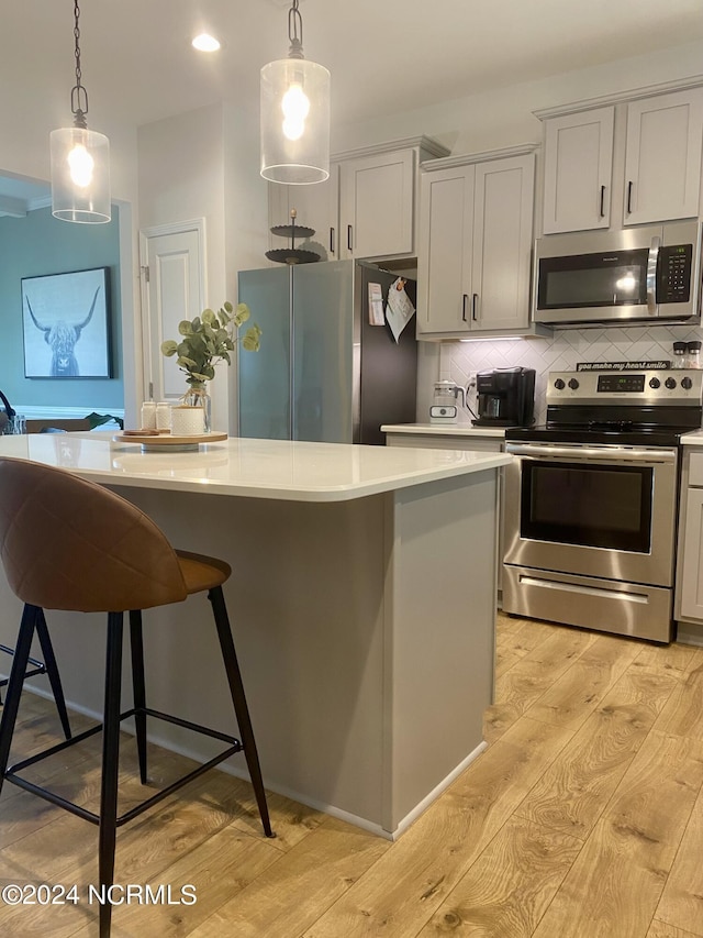 kitchen featuring a center island, stainless steel appliances, light countertops, decorative backsplash, and light wood-style floors