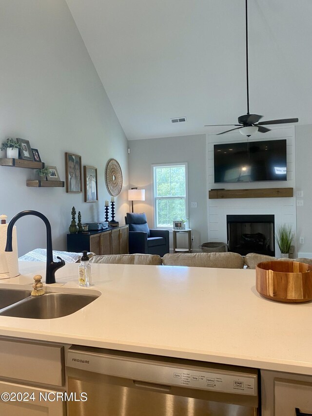 kitchen with a large fireplace, a sink, open floor plan, light countertops, and stainless steel dishwasher