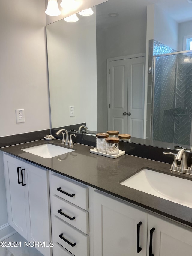 bathroom with a stall shower, a sink, and double vanity