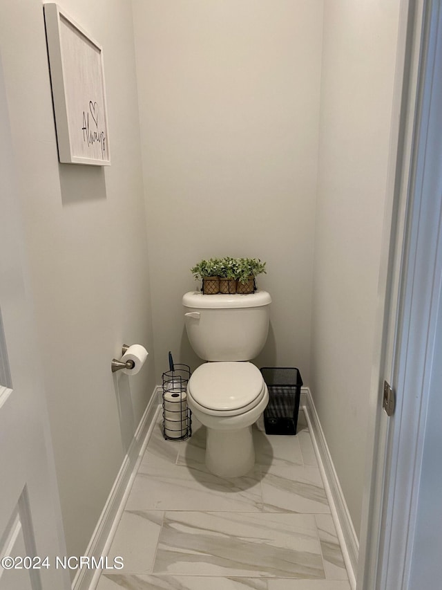 bathroom featuring marble finish floor, toilet, and baseboards