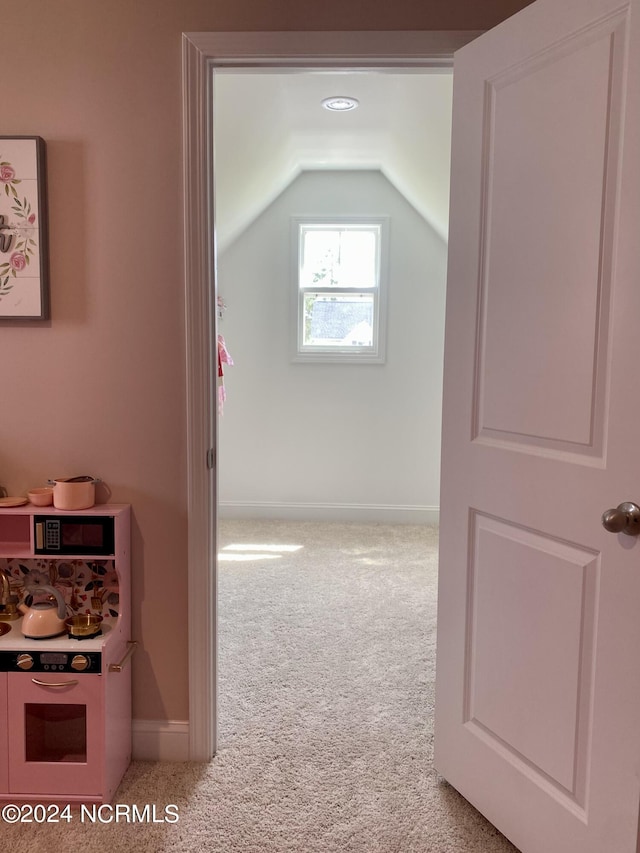 interior space with vaulted ceiling, carpet, and baseboards