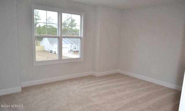 spare room featuring baseboards and light colored carpet