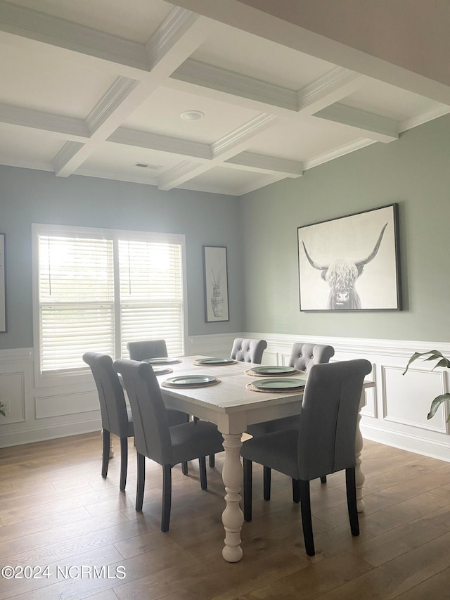 dining space with ornamental molding, beam ceiling, coffered ceiling, and wood-type flooring