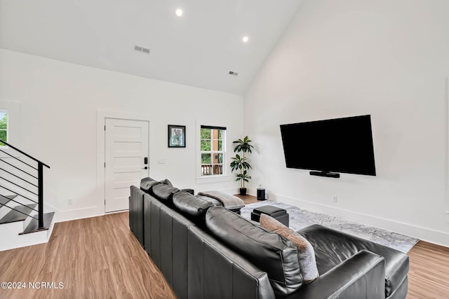 living room featuring high vaulted ceiling and light wood-type flooring