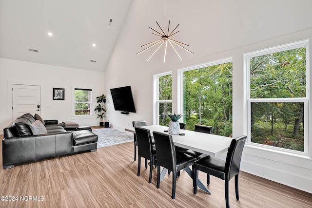 dining space with high vaulted ceiling, a notable chandelier, and light wood-type flooring