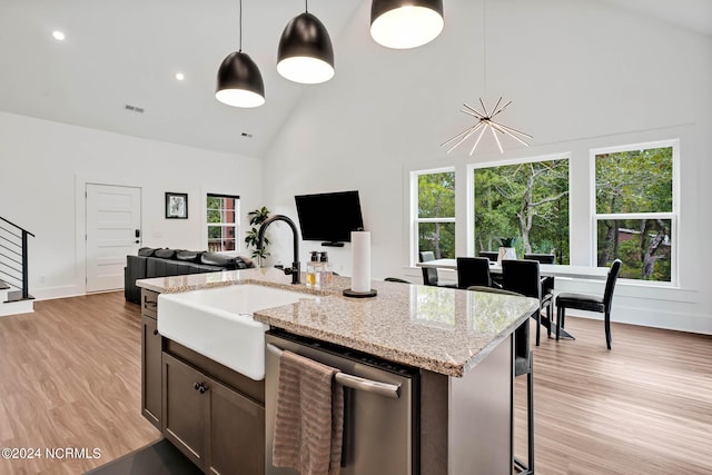 kitchen featuring sink, high vaulted ceiling, hanging light fixtures, light wood-type flooring, and dishwasher