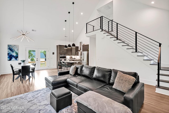 living room with french doors, high vaulted ceiling, and light wood-type flooring