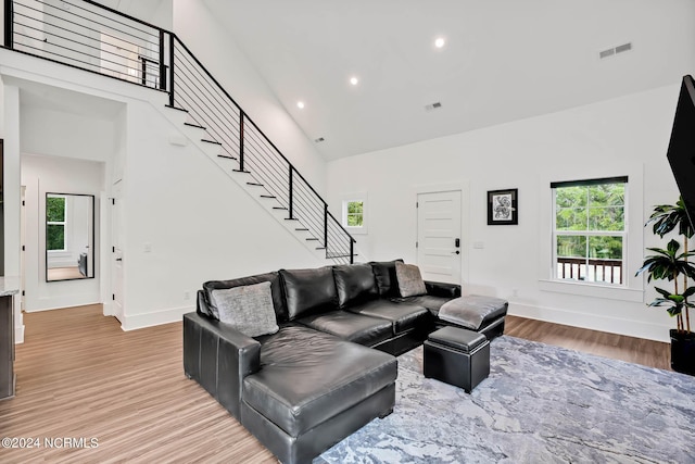 living room with a towering ceiling and wood-type flooring