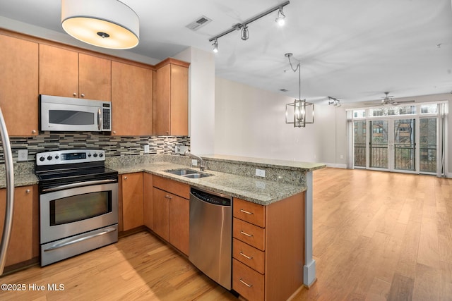 kitchen featuring sink, appliances with stainless steel finishes, backsplash, light hardwood / wood-style floors, and kitchen peninsula