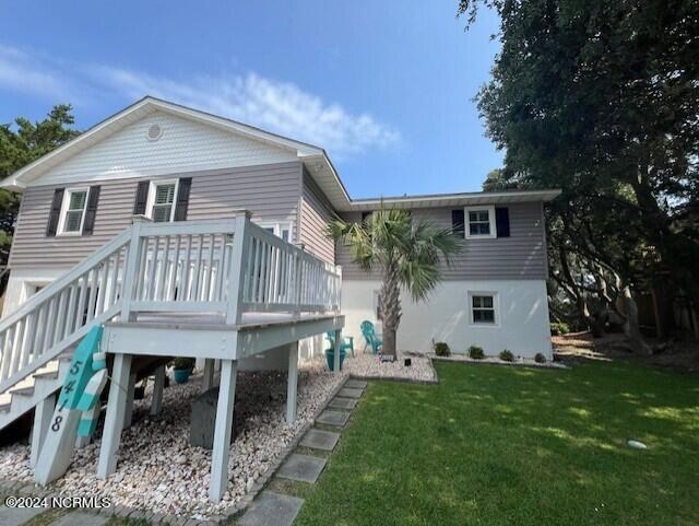 rear view of house with a wooden deck and a yard