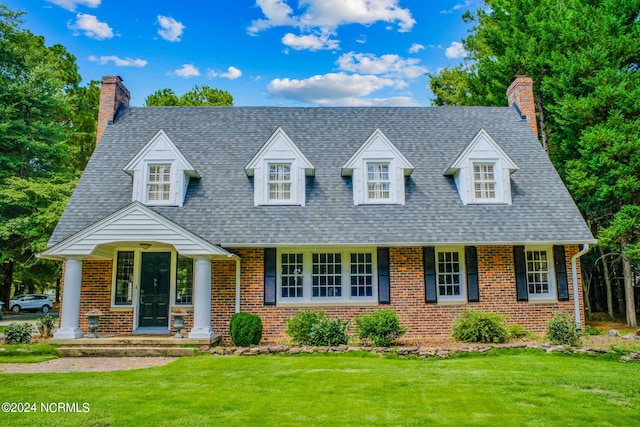 new england style home with a front yard and covered porch