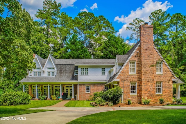 tudor house featuring a porch and a front lawn