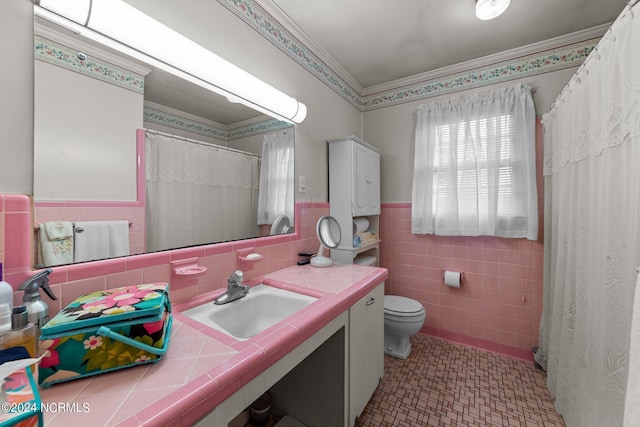 bathroom with tile patterned floors, toilet, tile walls, ornamental molding, and vanity