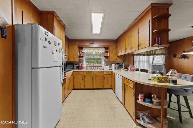 kitchen with a kitchen breakfast bar, sink, white appliances, and kitchen peninsula