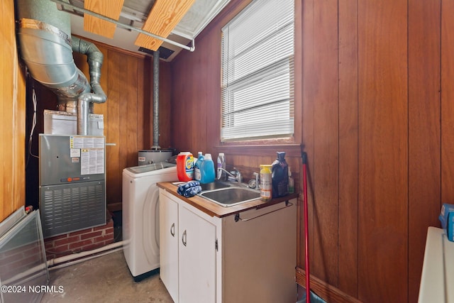 laundry area featuring washing machine and dryer, sink, and wooden walls