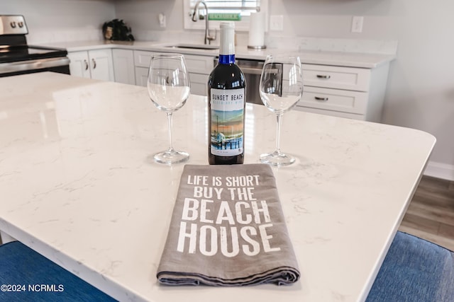 1409 Inlet St, Sunset Beach, NC 28468 - kitchen featuring stainless steel electric range, a sink, white cabinets, and light stone countertops