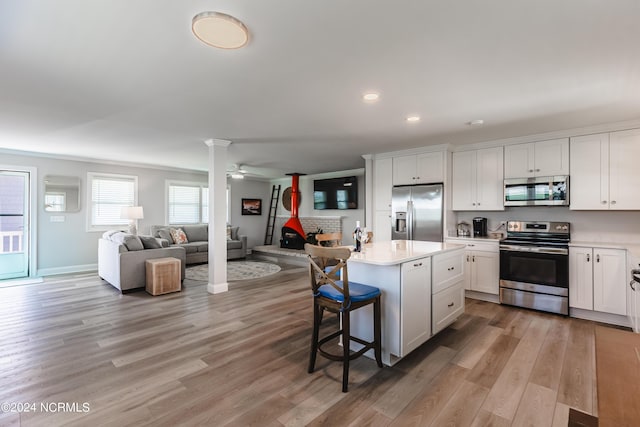 1409 Inlet St, Sunset Beach, NC 28468 - kitchen with stainless steel appliances, open floor plan, a kitchen breakfast bar, a kitchen island, and light wood-style floors