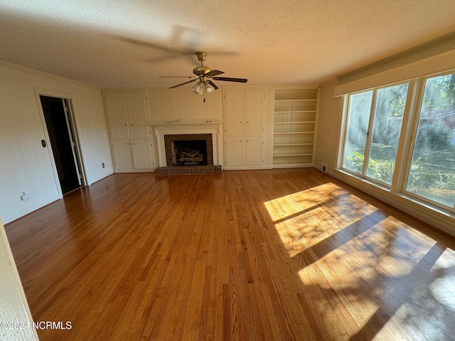 unfurnished living room with a fireplace, a textured ceiling, light hardwood / wood-style floors, and ceiling fan