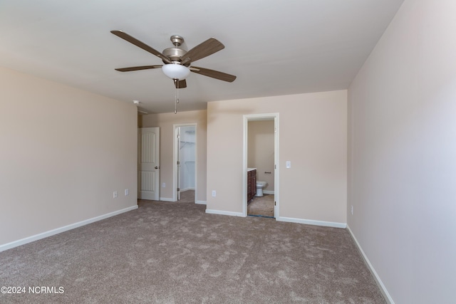 unfurnished bedroom featuring ensuite bathroom, a spacious closet, light colored carpet, a closet, and ceiling fan