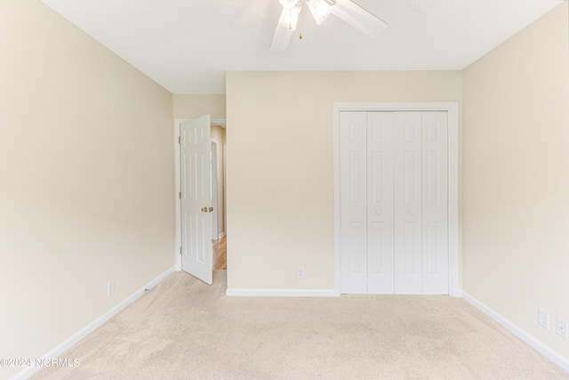 unfurnished bedroom with ceiling fan, light carpet, and a closet