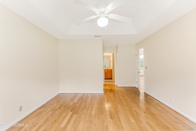 spare room featuring light hardwood / wood-style floors, a raised ceiling, and ceiling fan