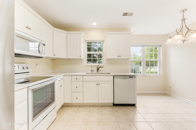 kitchen with sink, white appliances, light tile patterned floors, white cabinetry, and hanging light fixtures